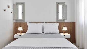 Un dormitorio ordenado con una cama grande, dos mesitas de noche con lámparas y dos ventanas con persianas.