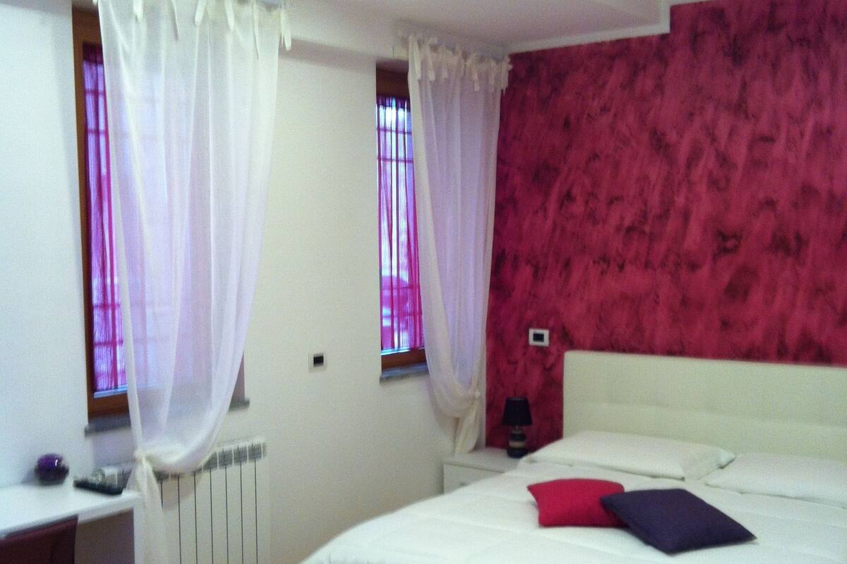 Une chambre à coucher avec un lit, un bureau et une fenêtre avec des rideaux.