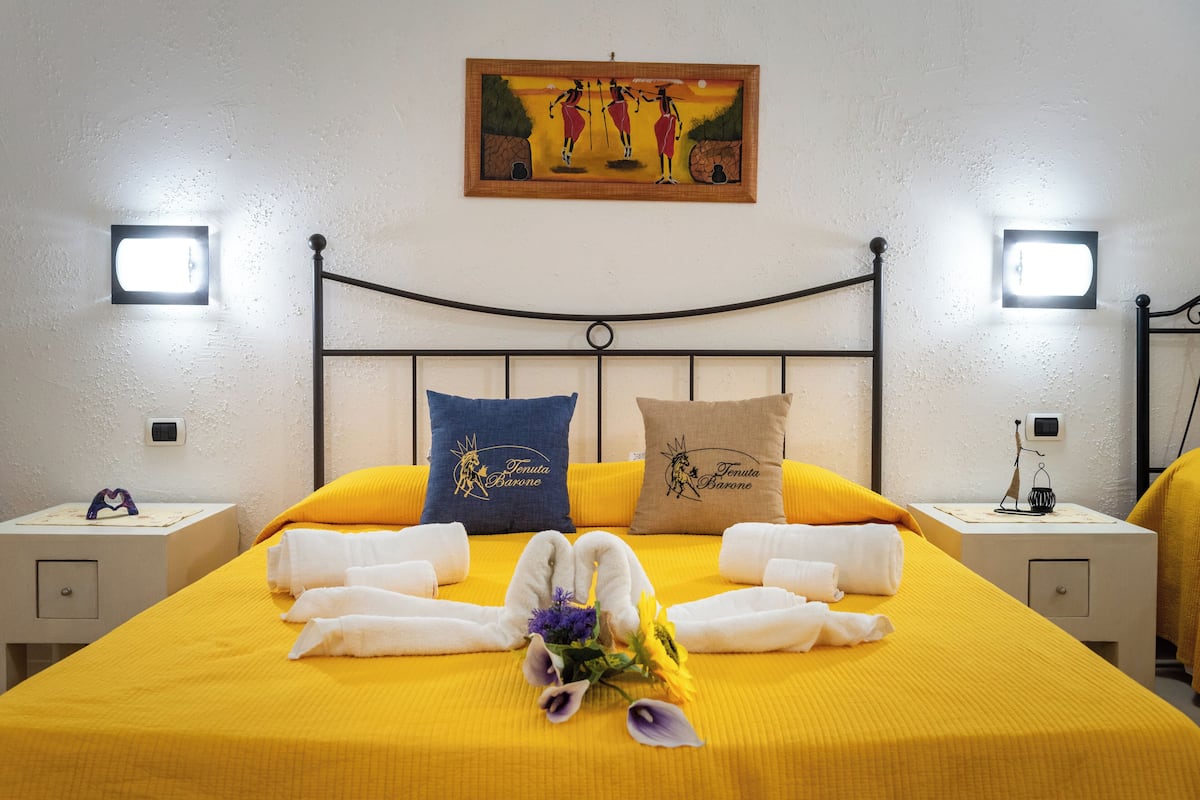 Une chambre d’hôtel avec un lit, deux oreillers, une table de chevet et un tableau accroché au mur.
