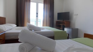 A hotel room with two beds, a television, and an air conditioning unit.