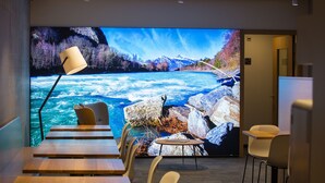 A conference room with a large screen displaying a river scene, wooden tables, and chairs. - b smart motel Landquart (Landquart)
