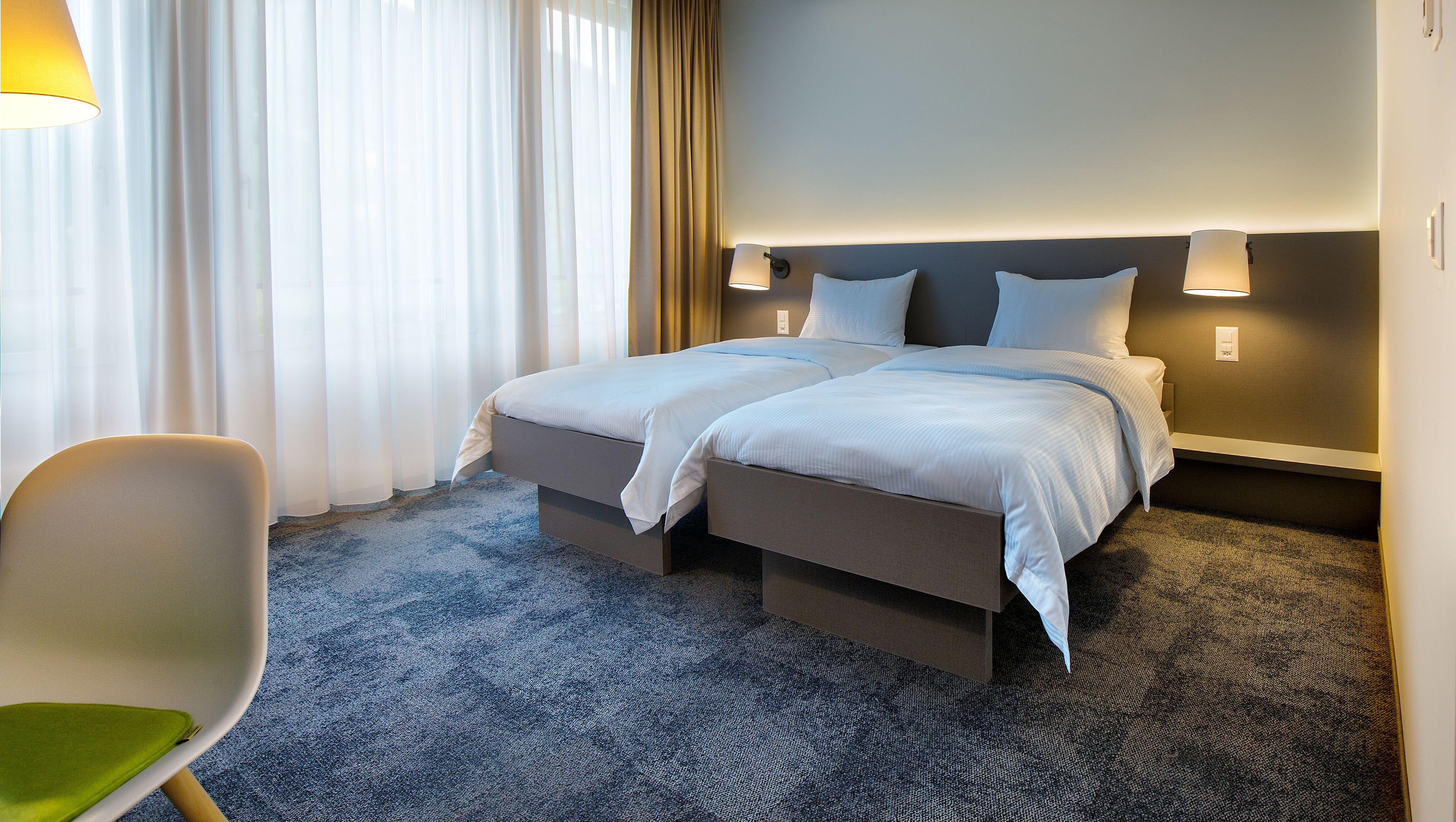 Habitación de hotel con dos camas, una silla y piso alfombrado.
