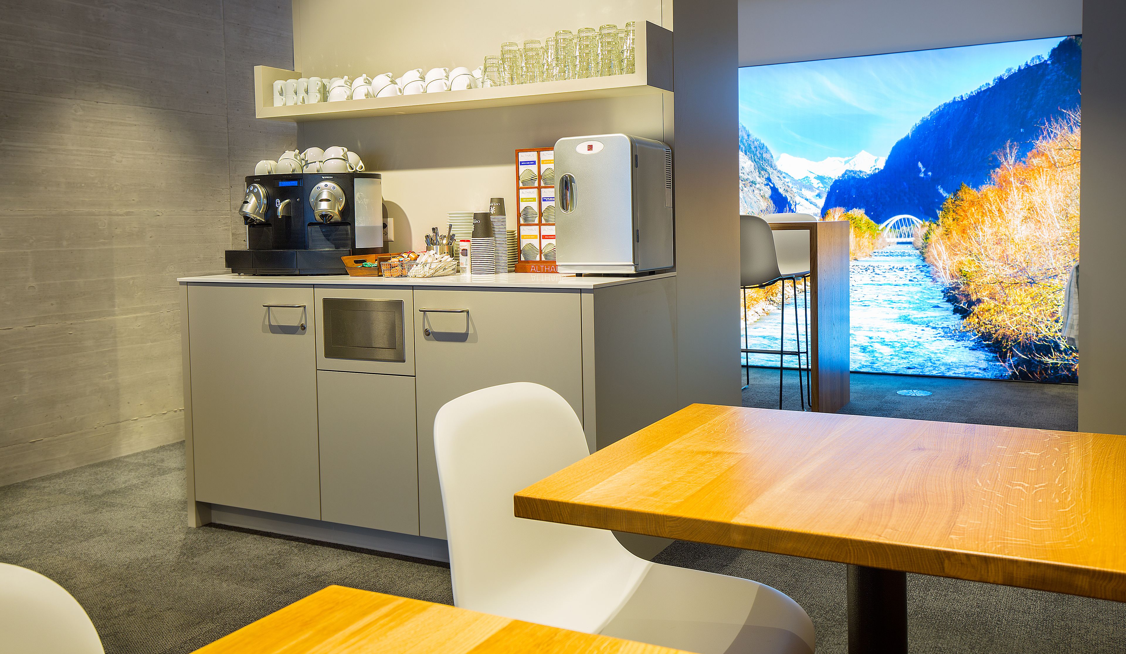 Une cuisine moderne équipée d’une machine à café, d’un service à thé et d’une grande fenêtre donnant sur les montagnes.