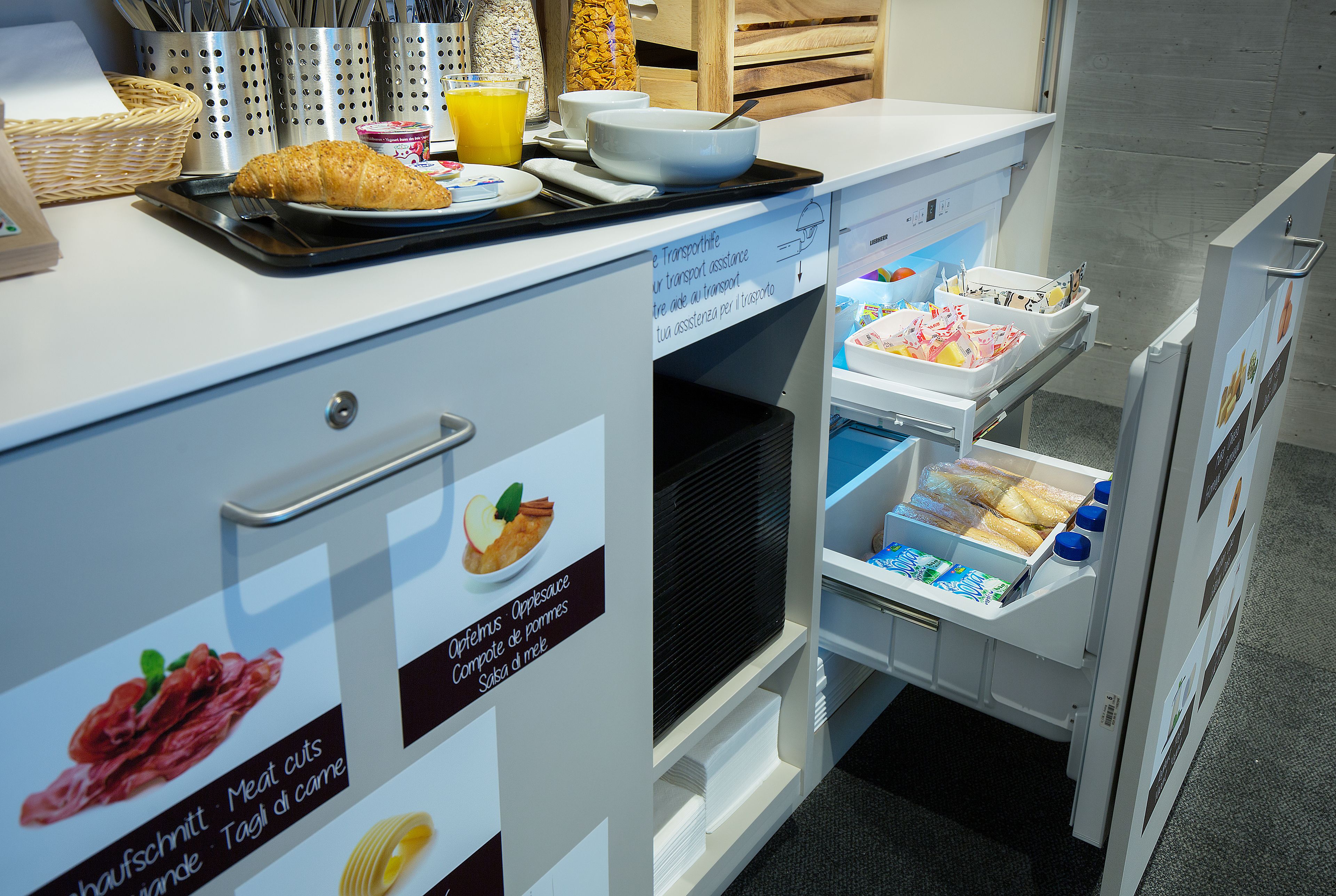 Una kitchenette con una bandeja de cruasanes, un bol y un vaso de jugo de naranja.