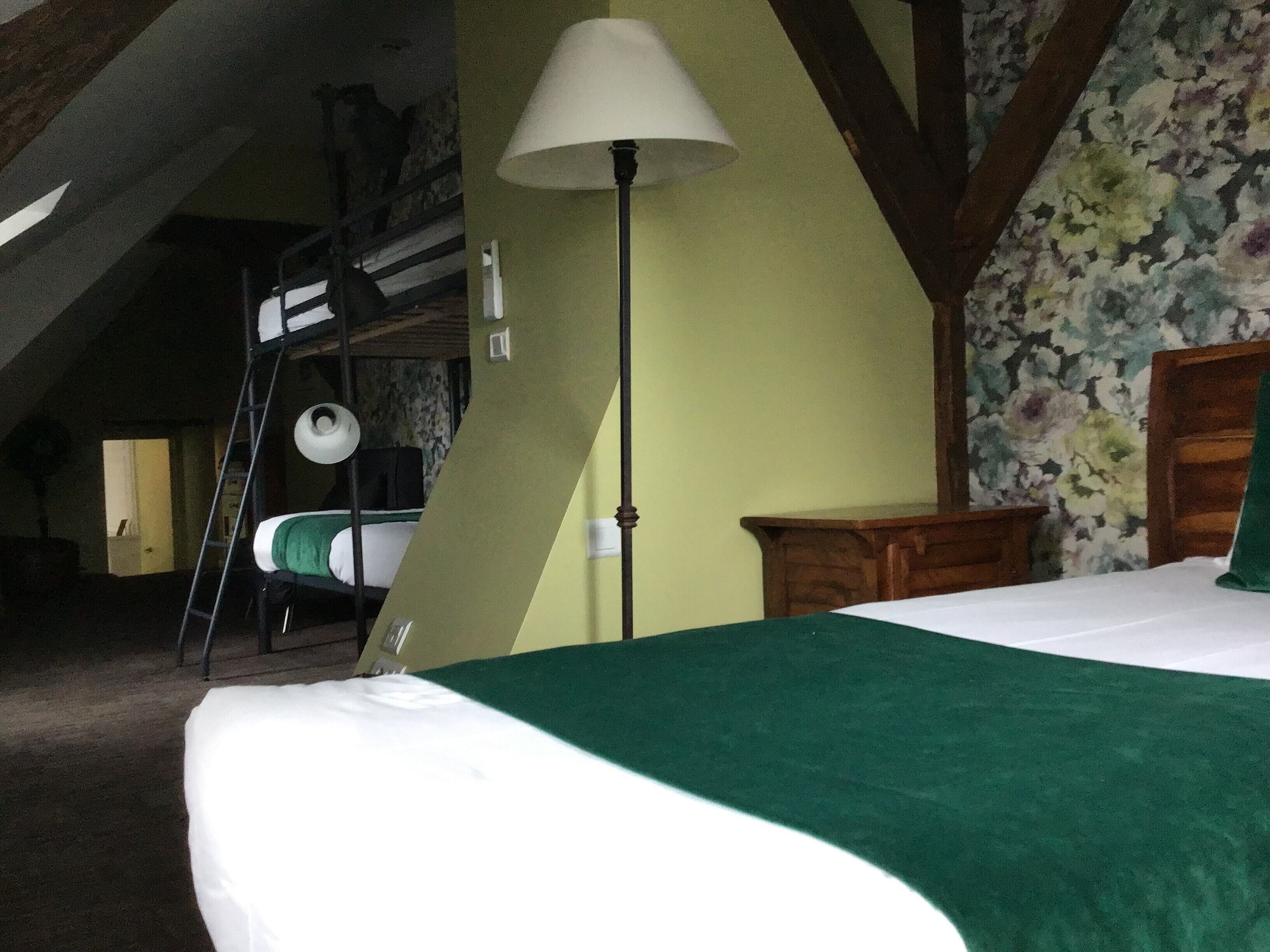 Una habitación con literas, una lámpara, un cabecero de madera y papel tapiz floral.