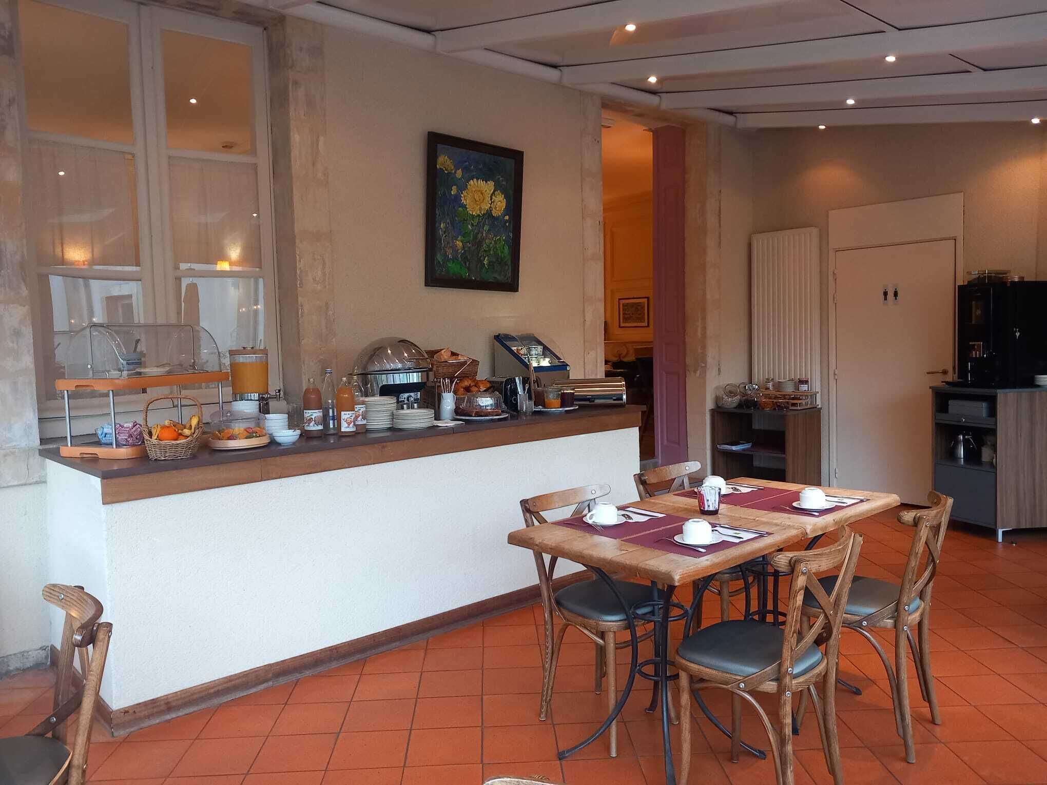 Una barra de desayuno con diversos alimentos y bebidas, una mesa de comedor con sillas y una zona de cocina al fondo.
