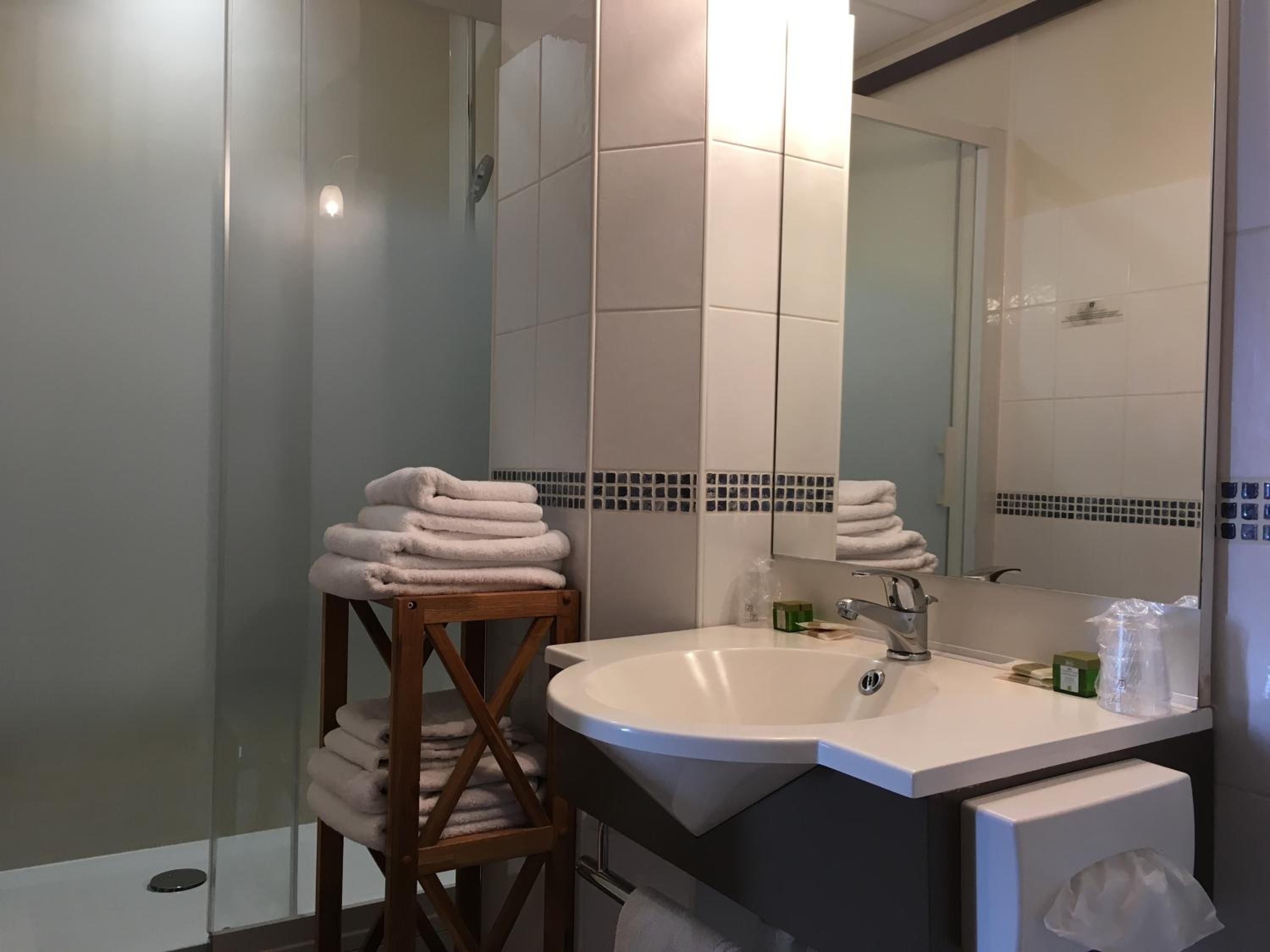 Un baño con lavamanos, espejo y toallero.