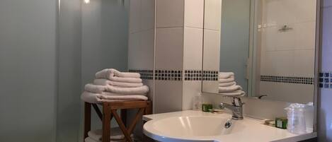 Un baño con lavamanos, espejo y toallero.