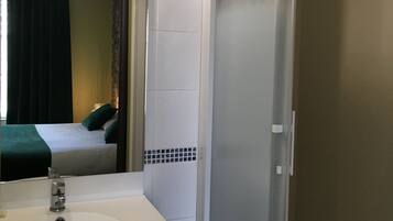 A bathroom with a white sink, a mirror, and a shower enclosure.