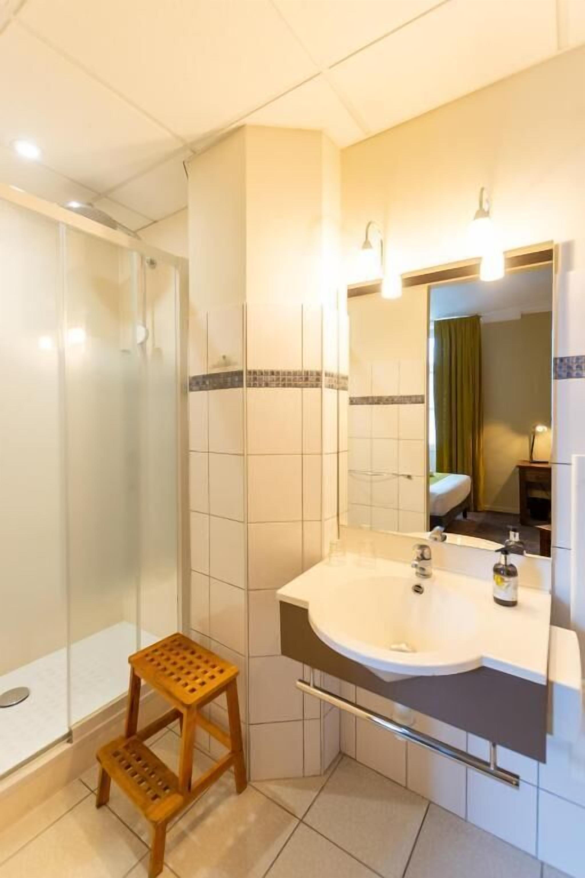 A bathroom with a shower, a sink, and a mirror.