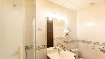Un baño con ducha, lavabo, inodoro y un espejo con iluminación.
