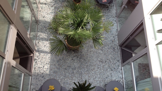 A top-down view of a courtyard with a central seating area, surrounded by potted plants and a patterned floor. - LoftVerona (Verona)