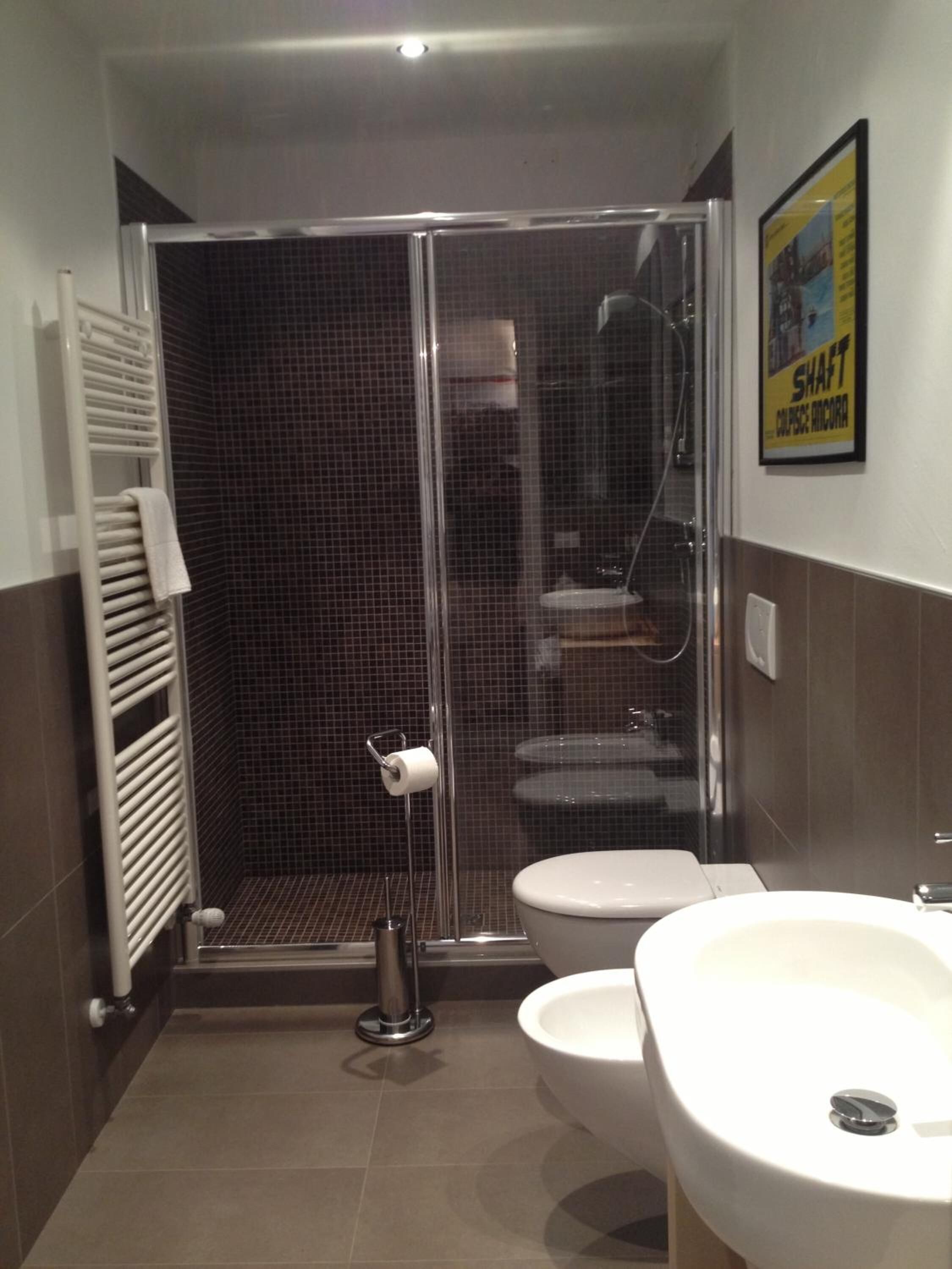 A modern bathroom with a glass-enclosed shower, two sinks, and a toilet.