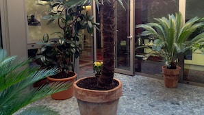 A courtyard with potted plants, a glass door, and a tiled floor. - LoftVerona (Verona)