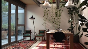 A dining area with a wooden table, green upholstered chairs, and a red patterned rug. - LoftVerona (Verona)