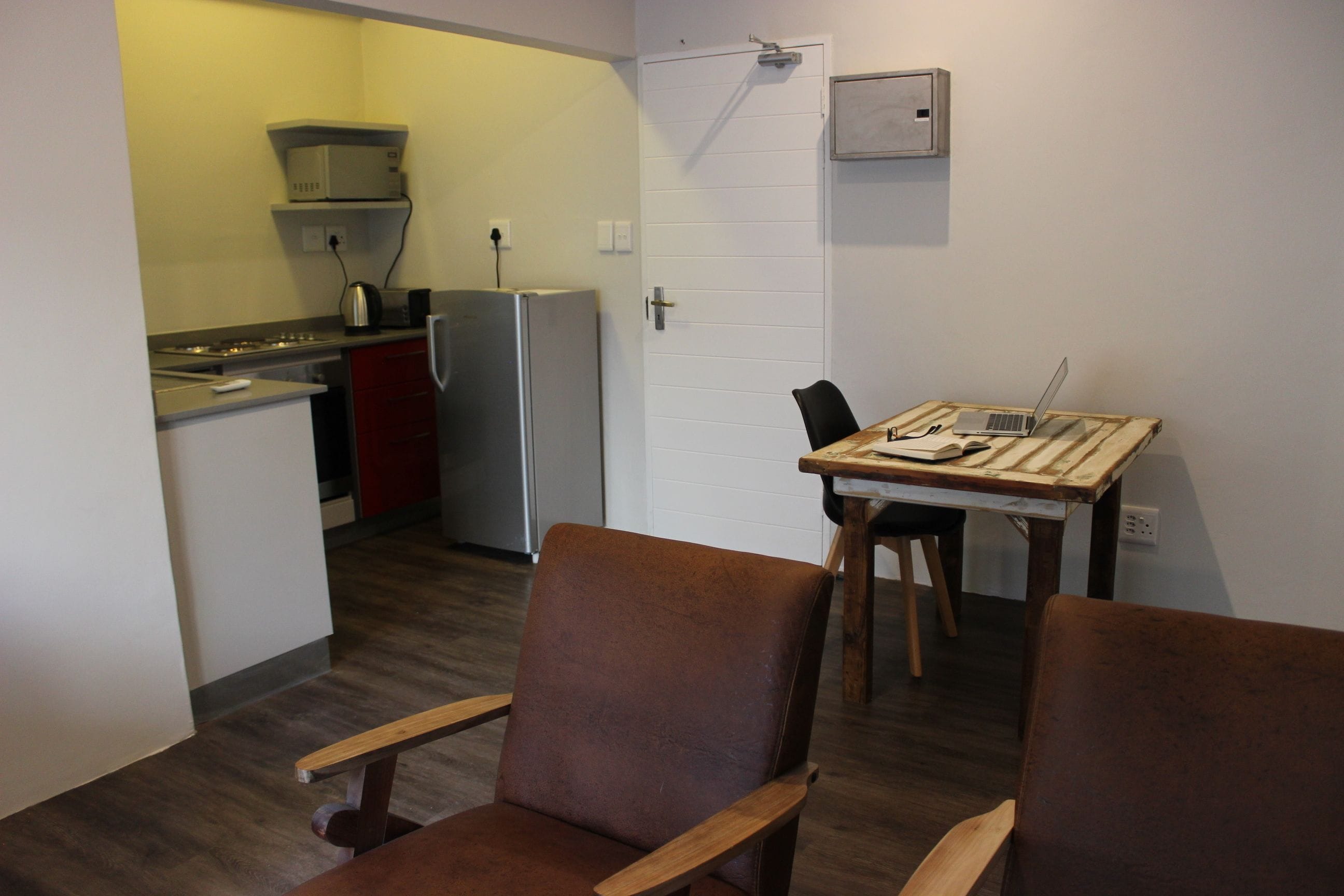 A compact kitchen with a refrigerator, microwave, and a small dining table with chairs.