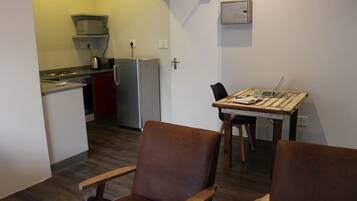 A compact kitchen with a refrigerator, microwave, and a small dining table with chairs.