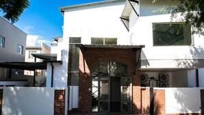 A modern building with a white facade and a brick entrance. - Zeederberg Corner (Paarl)