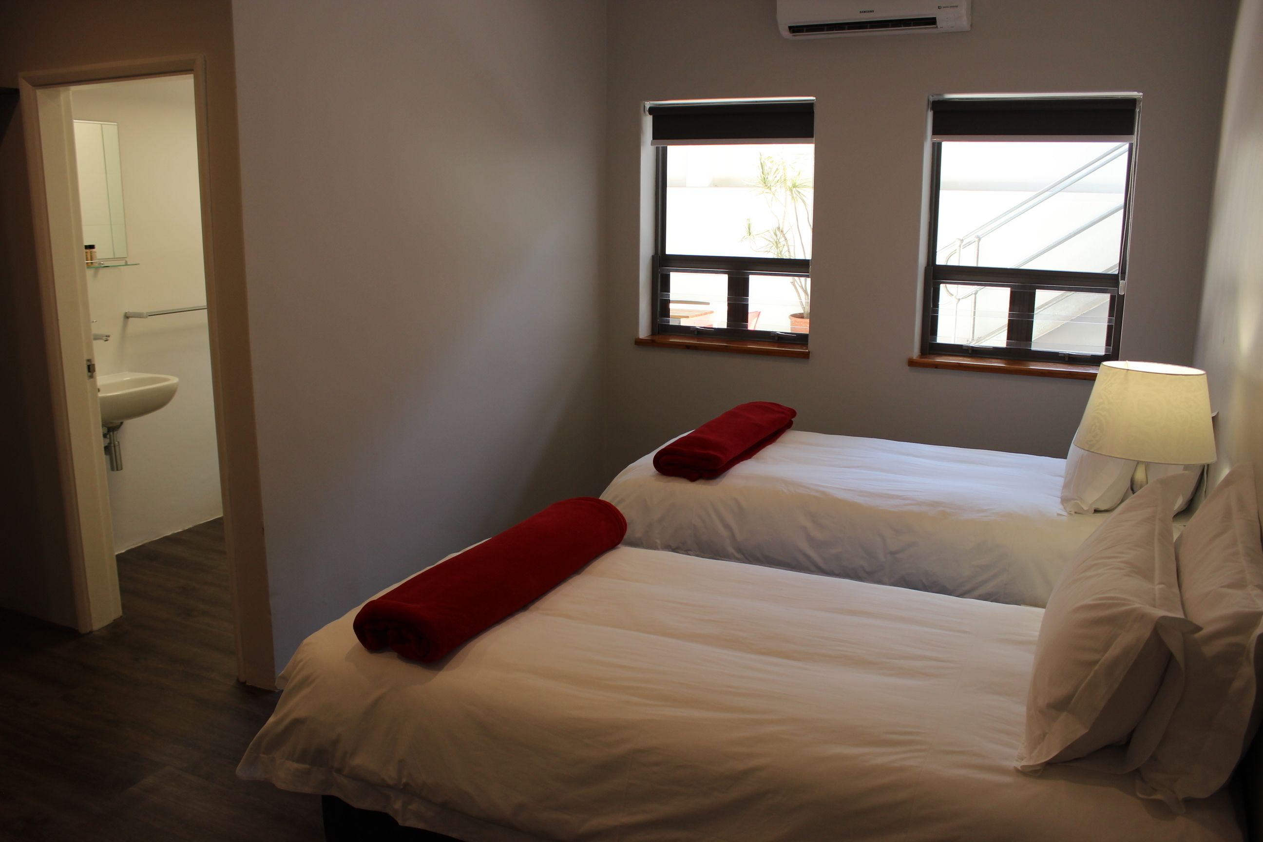 Une chambre d’hôtel avec deux lits, une fenêtre donnant sur un paysage agréable, un lavabo et une lampe.