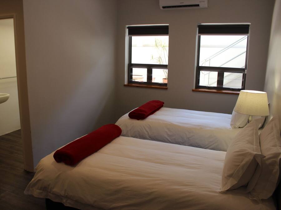 Une chambre d’hôtel avec deux lits, une fenêtre donnant sur un paysage agréable, un lavabo et une lampe.