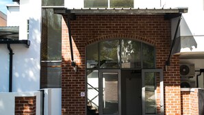 A building with a white facade, a brick entrance, and a glass door. - Zeederberg Corner (Paarl)