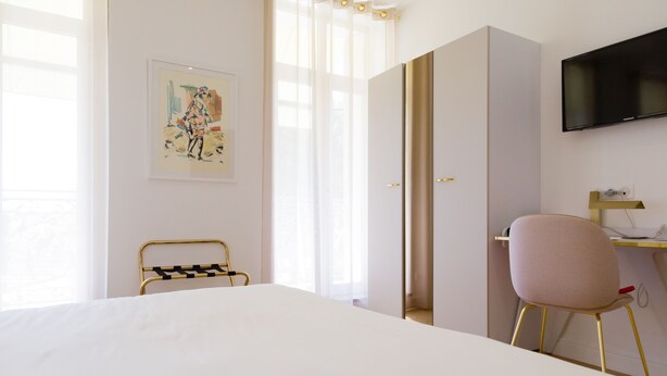 A hotel room with a large bed, a desk with a chair, a television, and a painting on the wall. - Hotel Cafe Glacier Le XIX (Béziers)