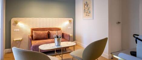 A cozy room with a sofa, two chairs, a small table, and a wall-mounted light fixture.