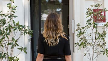 A woman in a black dress walking towards a hotel entrance labeled 'XIX HOTEL'.
