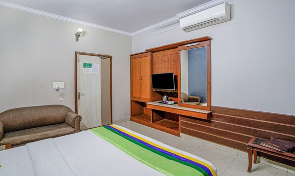 Una habitación de hotel con una cama, un armario de madera, un televisor y una mesita con un hervidor.