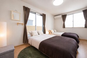 A hotel room with two beds, a bedside table, a lamp, and a window with curtains. - Tinker Bell (Osaka)