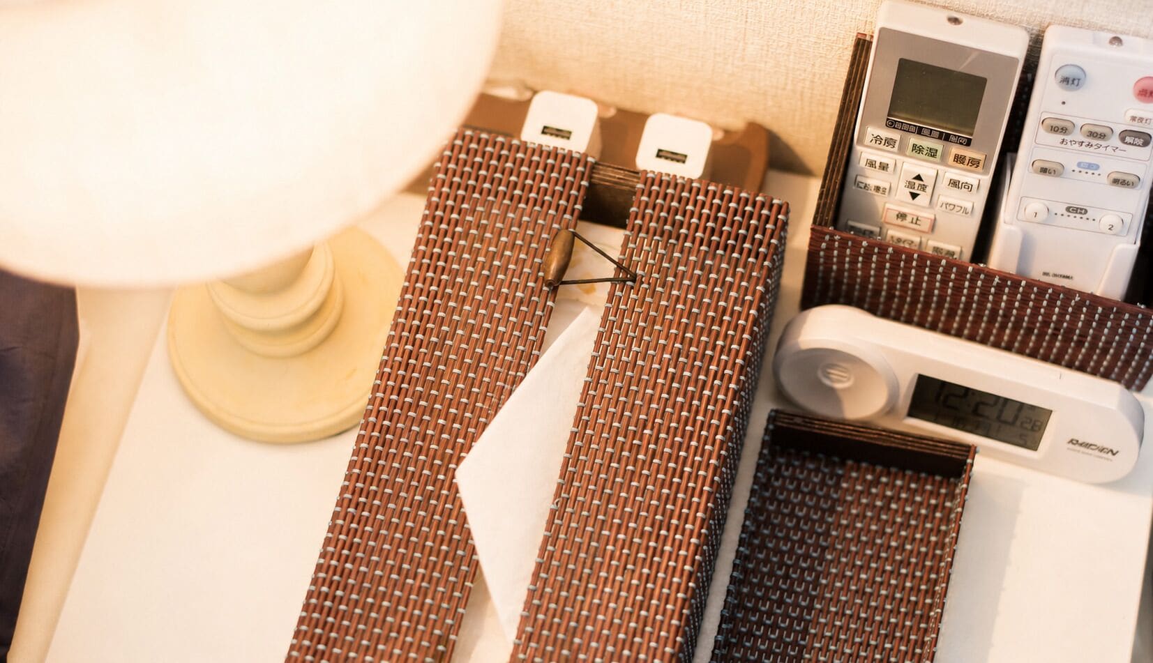 Een hotelkamer met een bed, een lamp, een digitale klok en een collectie stropdassen.
