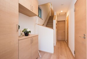 A modern hallway with wooden flooring, a staircase, and a door leading to another room. - Tinker Bell (Osaka)