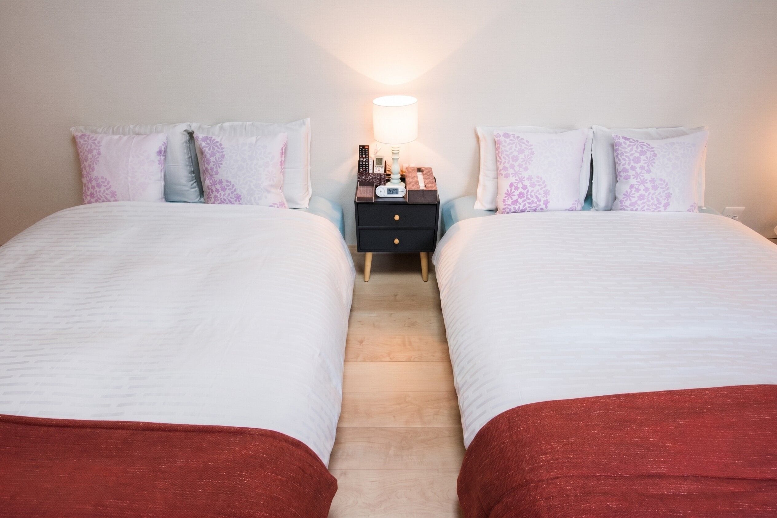 Habitación de hotel con dos camas, una mesita de noche y una lámpara fijada a la pared.