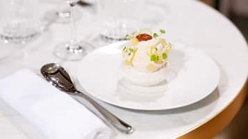 A white plate with a dessert on a marble table, accompanied by a folded napkin and a spoon.