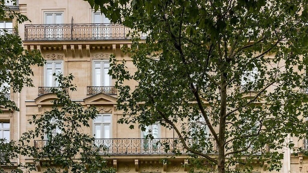 A multi-story building with a prominent red entrance, balconies with wrought iron railings, and storefronts for '99 HAUSSMANN' and 'HOTEL BOWMAN'. - Hôtel Bowmann, a Small Luxury Hotel of the World (Paris)