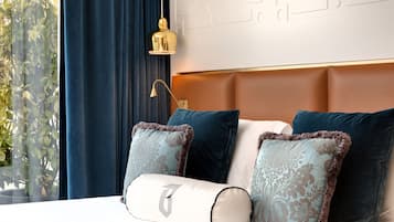 Habitación de hotel con cama, cortinas azules, una pared con diseño decorativo y una lámpara colgante.