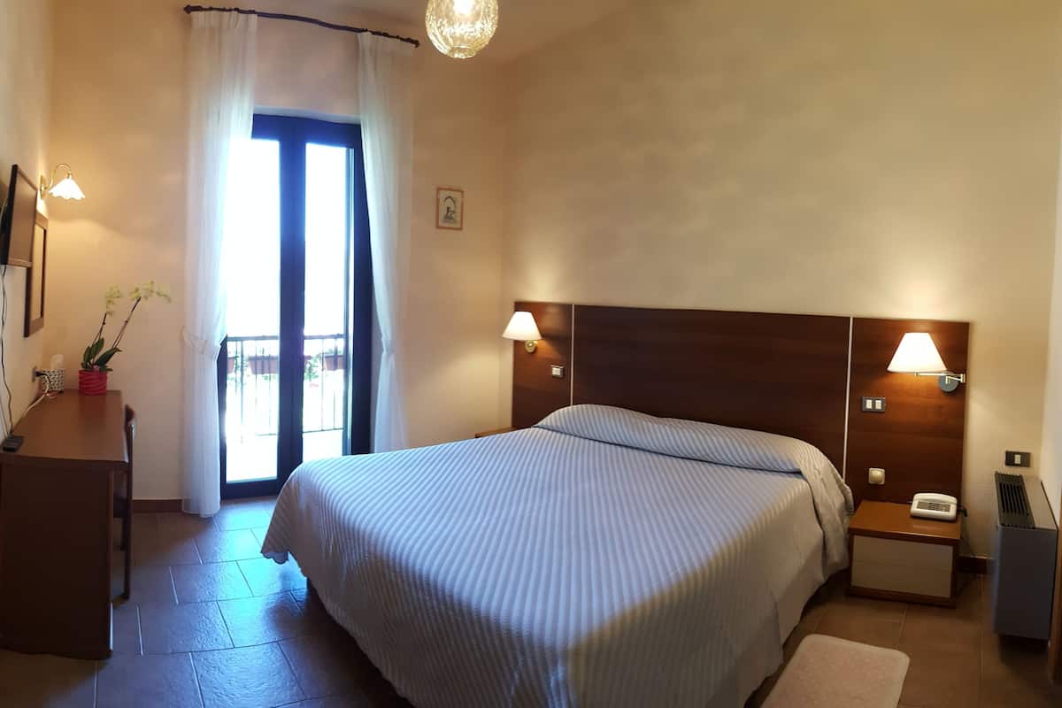Une chambre à coucher comprenant un lit, des lampes de chevet, une table de chevet, une commode, un miroir et une fenêtre avec des rideaux.