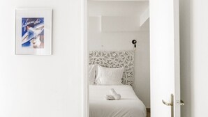 A bedroom with a white bed, a decorative headboard, and a framed picture on the wall.