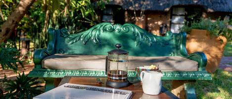 Un banco verde con una cafetera de vidrio y una taza blanca sobre una mesa de madera.