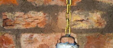A metal bell with the number 3 hanging on a brick wall.