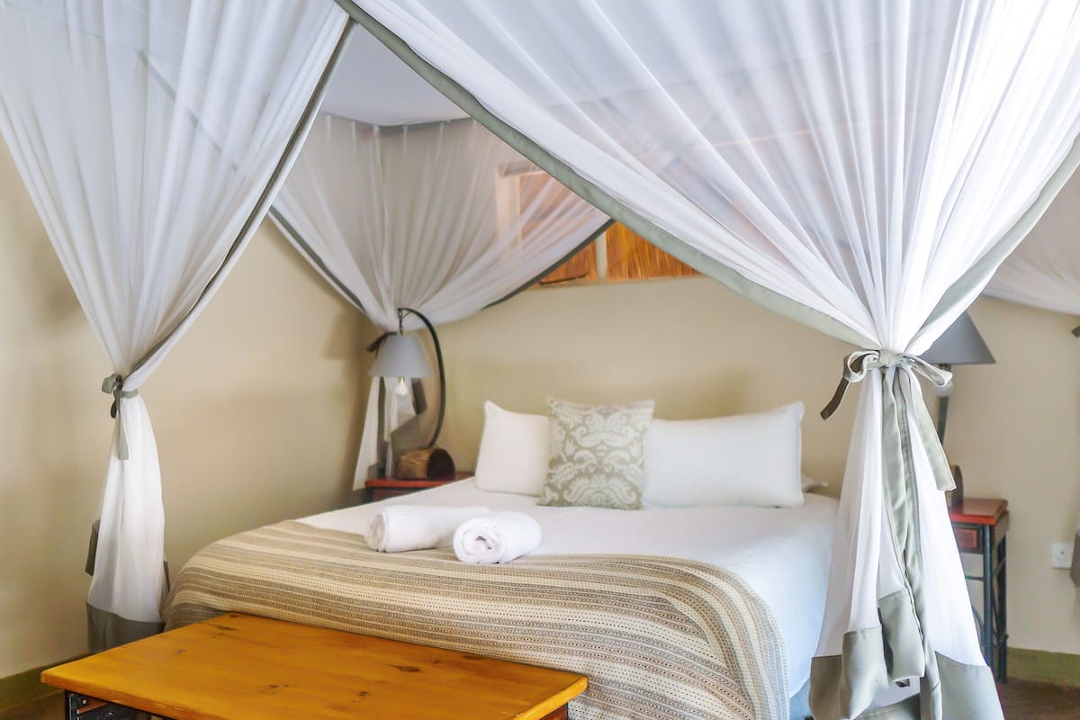 A room with a bed, a nightstand, a lamp, and a wooden table.