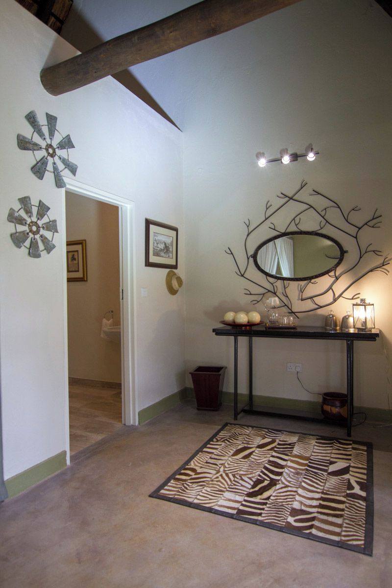 A room with a ceiling fan, a wall-mounted mirror, a small table with decorative items, and a zebra-patterned rug.