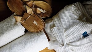 A wooden floor, a white towel, and a white robe with a tag.