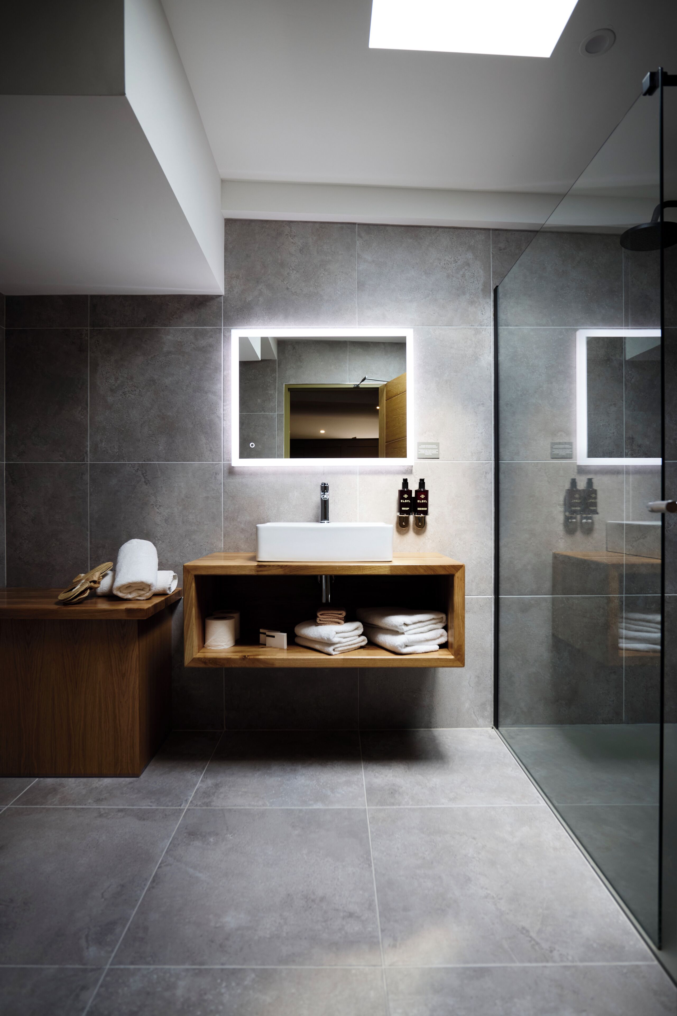 Une salle de bain moderne avec un grand miroir, un meuble-lavabo en bois et une cabine de douche en verre.