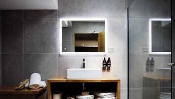 Une salle de bain moderne avec un grand miroir, un meuble-lavabo en bois et une cabine de douche en verre.