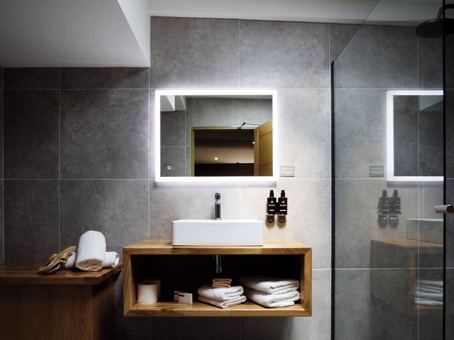 Une salle de bain moderne avec un grand miroir, un meuble-lavabo en bois et une cabine de douche en verre.