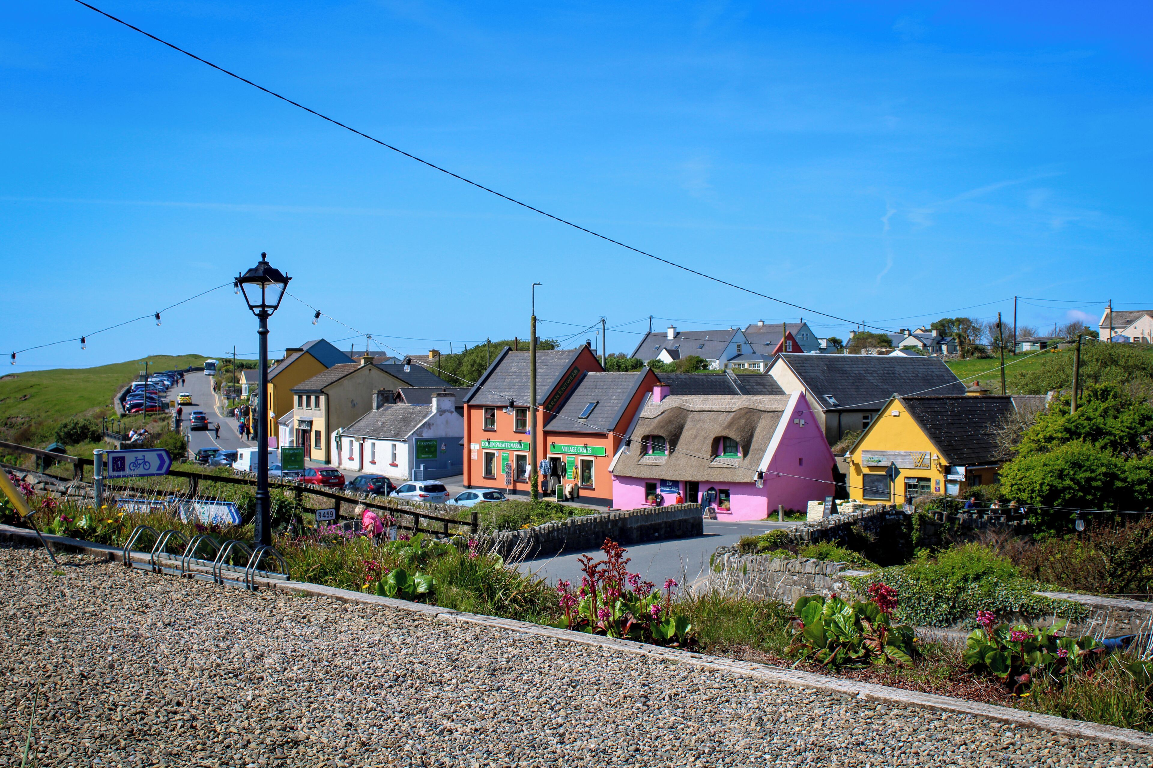 Un village côtier aux maisons aux couleurs vives, doté d’une route pavée et d’un mur de pierre.