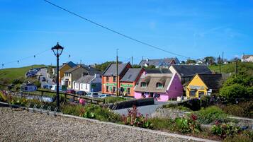 Un village côtier aux maisons aux couleurs vives, doté d’une route pavée et d’un mur de pierre.