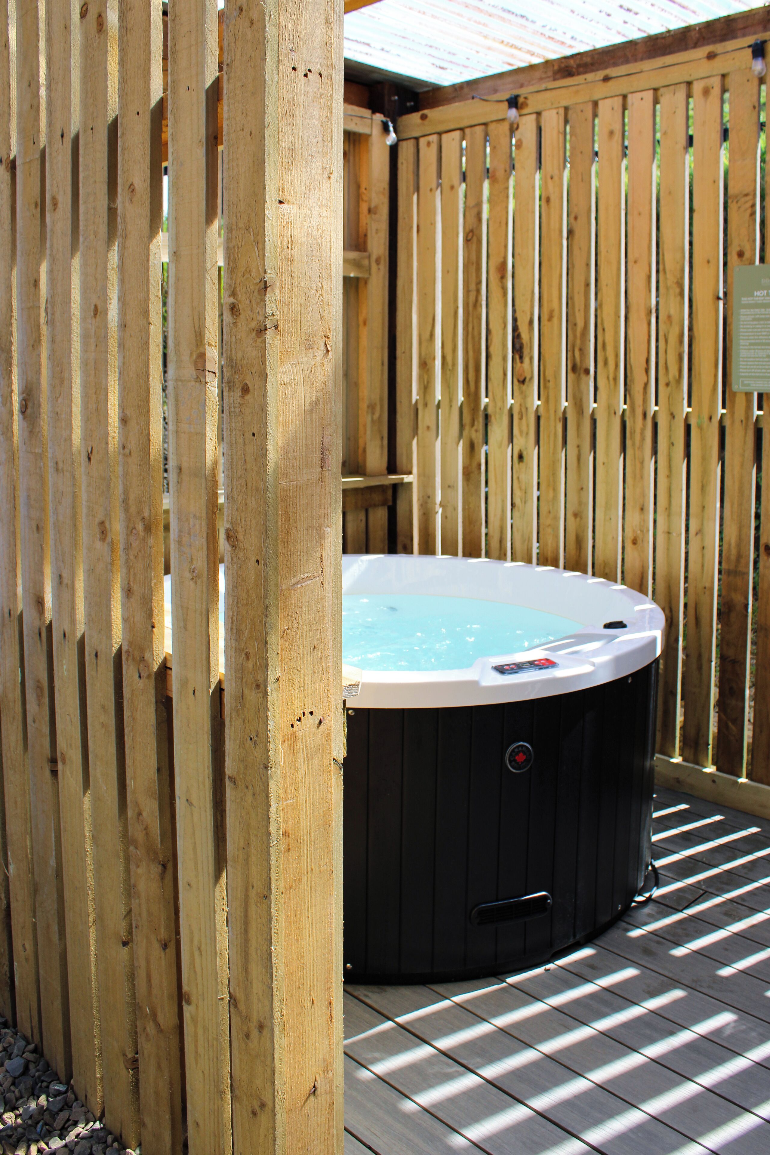 A hot tub in a wooden outdoor area with a tiled floor.