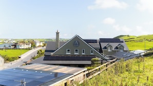 A building with a prominent 'A' logo on the roof, surrounded by green fields and houses.